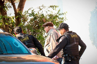 Francisco Cezário entrando em viatura do Gaeco, estacionada em frente à sua casa. (Foto: Henrique Kawaminami)