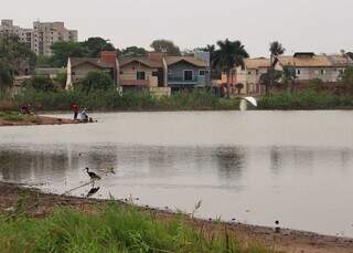 Areia às margens da lagoa e pescadores ao fundo na Lagoa Itatiaia em Campo Grande (Foto: Osmar Veiga) 