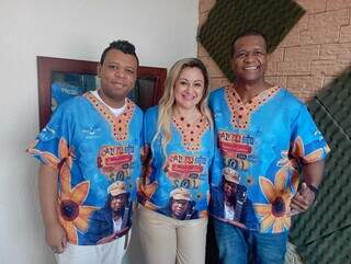 Produtor musical Vinicius Bola [à esquerda], compositora Sônia Jurado [centro] e o sambista Charlles André [à direita] posam com camiseta do samba-enredo “O Caminho que Vai Dar no Sol”, que está entre finalistas da Portela (Foto: Arquivo pessoal)