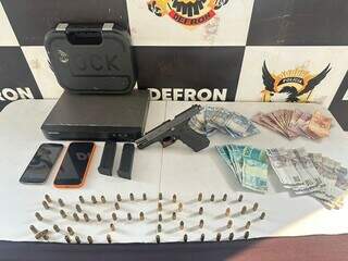 Pistola Glock, munição, aparelhos celulares e cédulas de real foram apreendidas durante o cumprimento de mandado de busca e apreensão. (Foto: Reprodução/Defron)