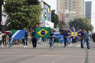 Em início de desfile, estudantes da rede estadual carregam as bandeiras do Brasil, de Mato Grosso do Sul e de Campo Grande (Foto: Osmar Veiga).