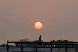 Homem caminha sob céu e sol enfumaçados, no Parque das Nações Indígenas (Foto: Henrique Kawaminami)