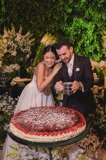 Bruna e Vitor finalizando o bolo durante o casamento.