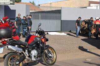 Corpo da vítima coberto com lençol branco em frente à oficina onde foi assassinado (Foto: Paulo Francis)