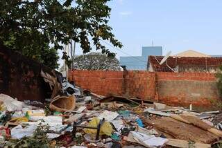 Terreno está tomado por lixo; ao fundo é possível ver a lateral do prédio da Vigilância em azul (Foto: Osmar Veiga)