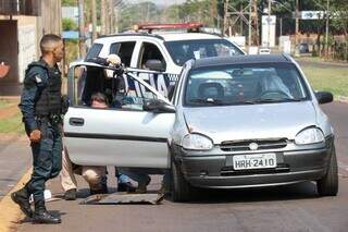 Policiais ao lado de carro ocupado pela vítima. (Foto: Henrique Kawaminami)