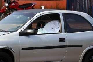 Corpo da vítima coberto por lençol dentro de carro. (Foto: Henrique Kawaminami)