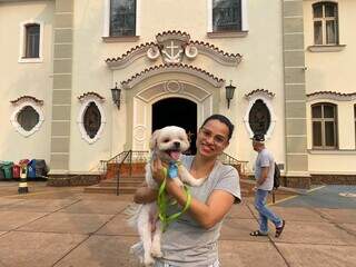 Danyelle segura o cachorro Romeu em frente à paróquia. (Foto: Clara Farias)