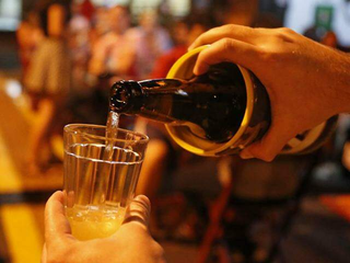 Consumidor serve copo de cerveja em bar no Centro de Campo Grande. (Foto: Arquivo/Campo Grande News)