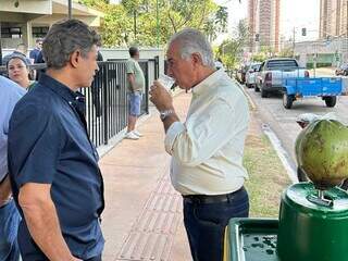 Reinaldo Azambuja (branco) toma coco em frente à Escola Municipal Lúcia Martins Coelho (Foto: Marcos Maluf)