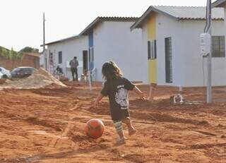 Criança brinca com bola de futebol em área de habitação popular (Foto: Paulo Francis)