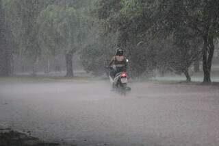 Motociclista atravessando área alagada em Campo Grande (Foto: Arquivo/Campo Grande News)