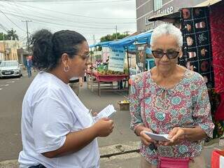 Idosa recebe planfleto com orientações sobre denunciar violência e se proteger de golpes (Foto: Marcos Maluf)