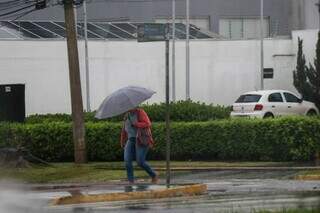 Mulher caminhando com guarda-chuva em Campo Grande (Foto: Henrique Kawaminami)