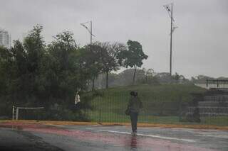 Pessoa caminhando em meio a chuva ao lado do Parque das Nações Indígenas (Foto: Henrique Kawaminami) 