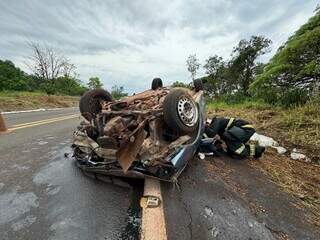 Carro com as quatro rodas para cima e bombeiro no local do acidente (Foto: Jornal da Nova)