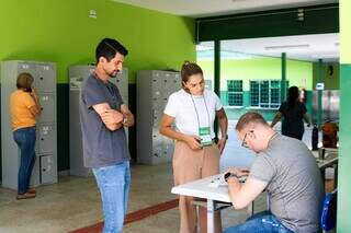 Rogério (em pé, com camiseta cinza) aguarda a conferência dos documentos para votar no segundo turno (Foto: Henrique Kawaminami)