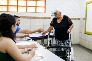 Mesário devolve o documento de Marilda, após ela votar (Foto: Henrique Kawaminami) 