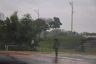 Pessoa caminhando no sábado em meio à chuva ao lado do Parque das Nações Indígenas (Foto: Henrique Kawaminami).