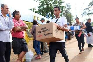 Voluntário carrega urna eletrônica antes de abrir escola para votação (Foto: Henrique Kawaminami)