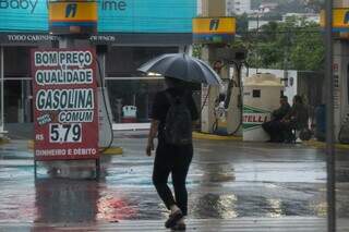 Homem caminha com guarda-chuva pelo Centro de Campo Grande (Foto: Henrique Kawaminami)