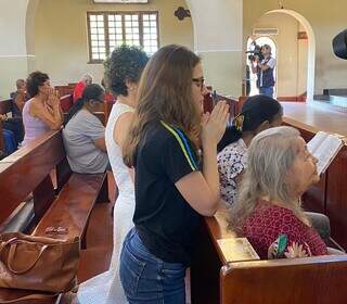 Com a caneta em mãos, Carla Liberati reza durante a celebração religiosa. (Foto: Henrique Kawaminami)