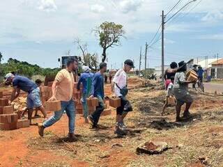 Moradores se juntam para tirar os tijolos de terreno (Foto: Marcos Maluf)