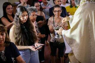 À esquerda, Letícia segura a caneta com outros fiéis em volta. (Foto: Henrique Kawaminami)