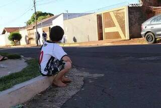 Criança sentada na calçada observando a rua. (Foto: Arquivo/Campo Grande News) 