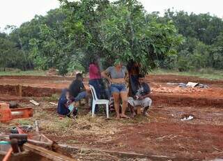 Grupo de pessoas tenta se proteger da chuva em uma pequena árvore (Foto: Osmar Veiga)