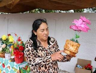 Lídia mostrando o vaso de flor montado por ela para vender no Dia de Finados (Foto: Osmar Veiga)