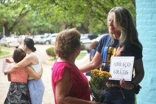 Voluntária segura placa &#34;abraço grátis&#34; enquanto conversa com Maria (Foto: Paulo Francis)