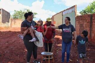 Família em terreno onde será construída a casa do zero (Foto: Osmar Veiga)