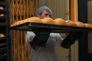 Padeiro retira pães assados de forno industrial. (Foto: Arquivo/Campo Grande News)