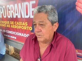 Carlos Antônio sentado em ponto de ônibus, dando entrevista sobre o preço da carne (Foto: Clara Farias)