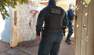 Policiais militares e sangue no muro da casa onde André foi baleado (Foto: Elenize Oliveira | Cenário MS)