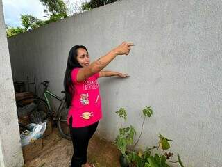 Beatriz Regina, de 28 anos, mostrando altura em que água chegou (Foto: Marcos Maluf)