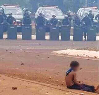 Garoto sentado no meio-fio e, ao fundo, policiais do Batalhão de Choque, após confronto (Foto: Direto das Ruas)