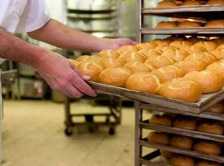 Padeiro retira forma cheia de pães de forno elétrico. (Foto: Arquivo/Campo Grande News)