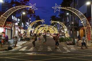 Campo-grandenses circulam na Rua 14 de Julho, iluminada com arcos e estrelas cadentes. (Foto: Enryck Sena)