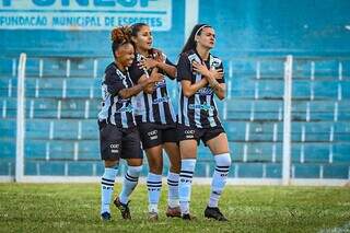 Jogadoras do Galo comemoram vitória com abraço no gramado. (Foto: Rodrigo Moreira/FFMS)