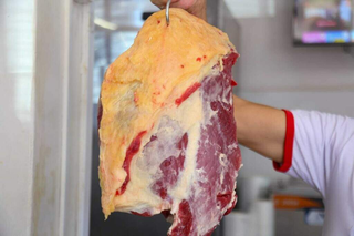 Açougueiro mostra corte de carne em açougue de Campo Grande. (Foto: Arquivo/Alex Machado)