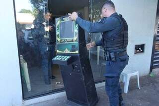 Policiais saindo com a máquina do local da apreensão (Foto: Paulo Francis)