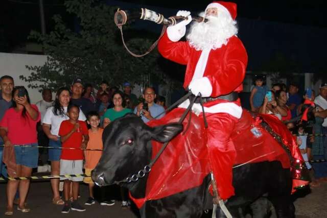 Papai Noel pantaneiro chega montado em touro e com berrante