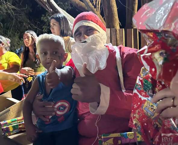 Jantar e Papai Noel com barba improvisada animam Natal de crian&ccedil;as de comunidade