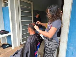 Voluntária corta cabelo de acolhido; ações assim são frequentes no local neste fim de ano (Foto: Divulgação)