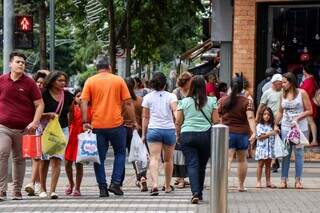 Consumidores atravessando rua, com sacolas, no Centro de Campo Grande (Foto: Henrique Kawaminami)