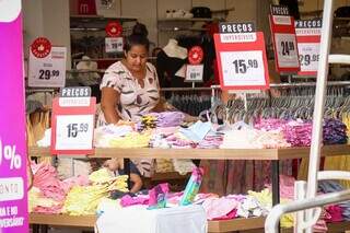 Mulher confere produtos em oferta em comércio do Centro. (Foto: Henrique Kawaminami)