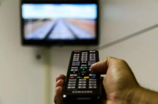 Homem segura controle para ligar televisão. (Foto: Arquivo/Campo Grande News)