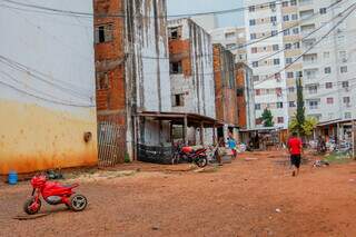 Crianças brincando junto às torres inacabadas do Residencial Atenas com prédio de outra construtora ao fundo. (Foto: Paulo Francis)